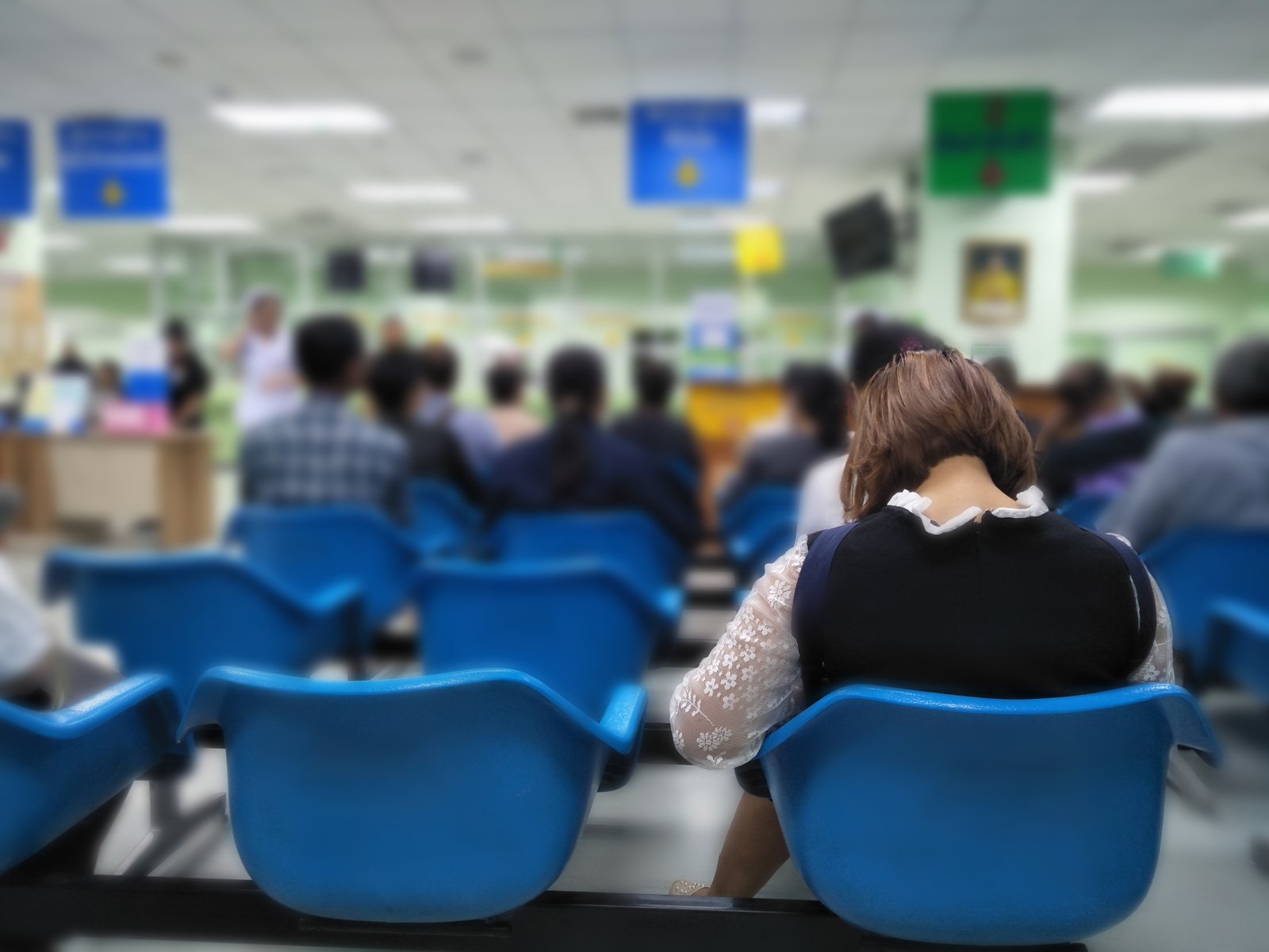 Sala de espera con personas sentadas en sillas azules