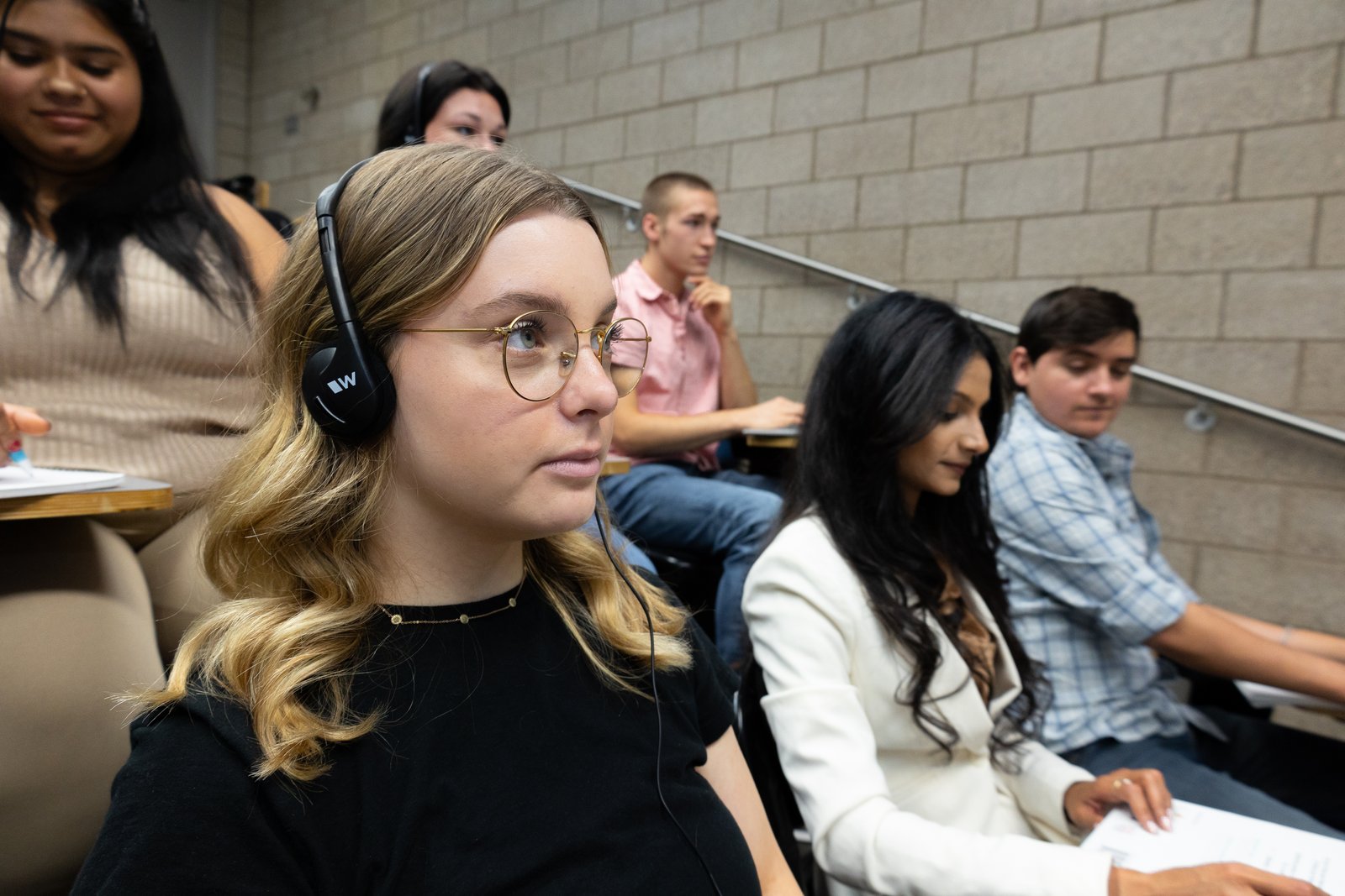 Estudiantes en un aula, una de ellas con auriculares